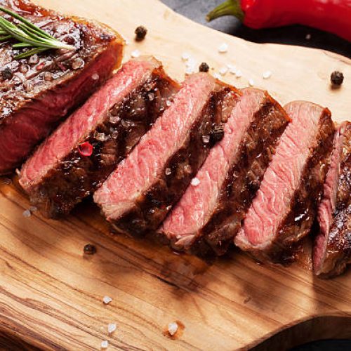 Grilled striploin sliced steak on cutting board over stone table